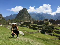 Photo of study abroad student Brianna Rivera kneeling on the grass in Peru.